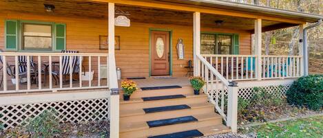 A wooden house with a porch, steps, and outdoor seating.
