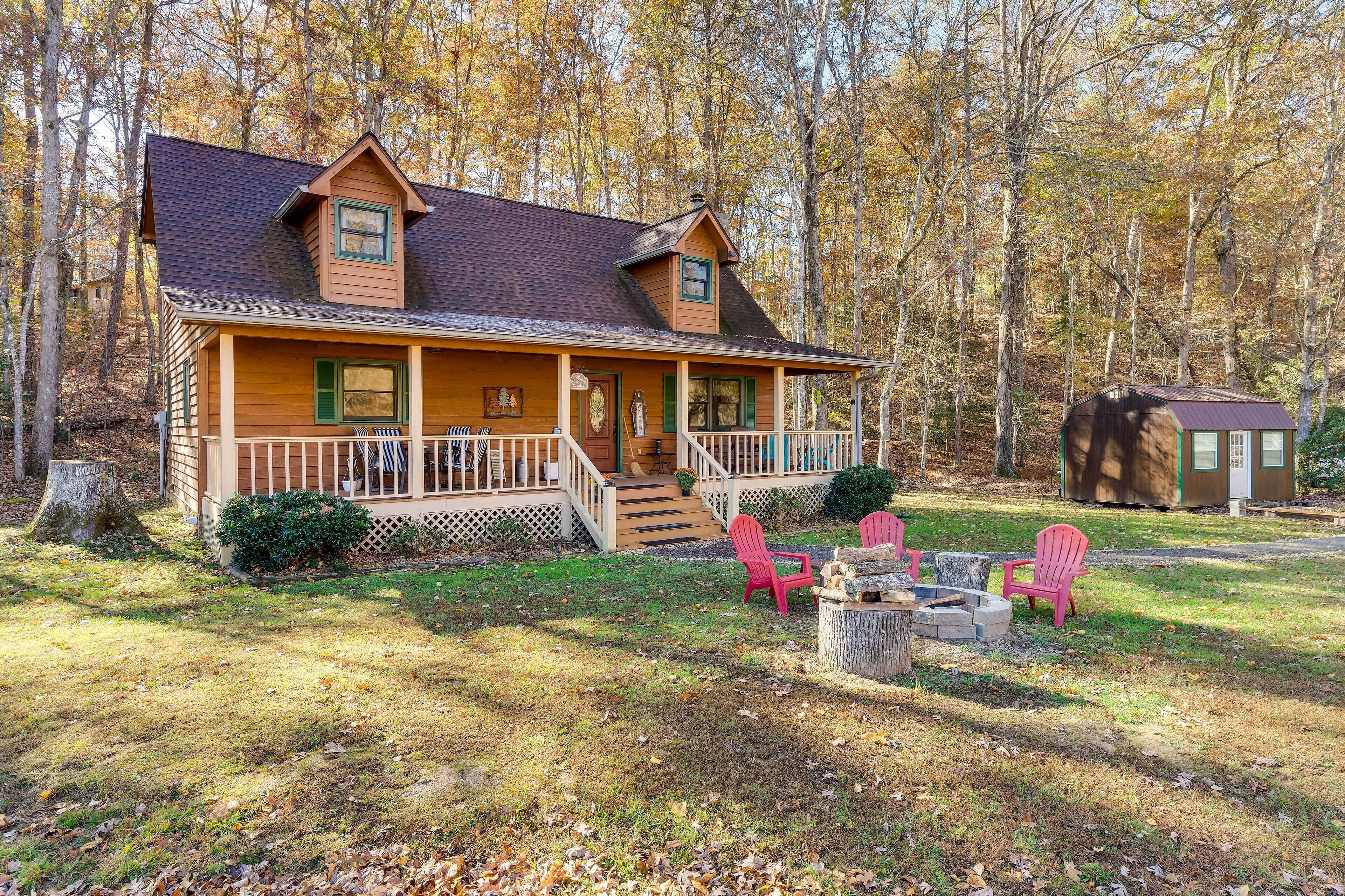 A cabin with a porch, two red Adirondack chairs, and a fire pit.