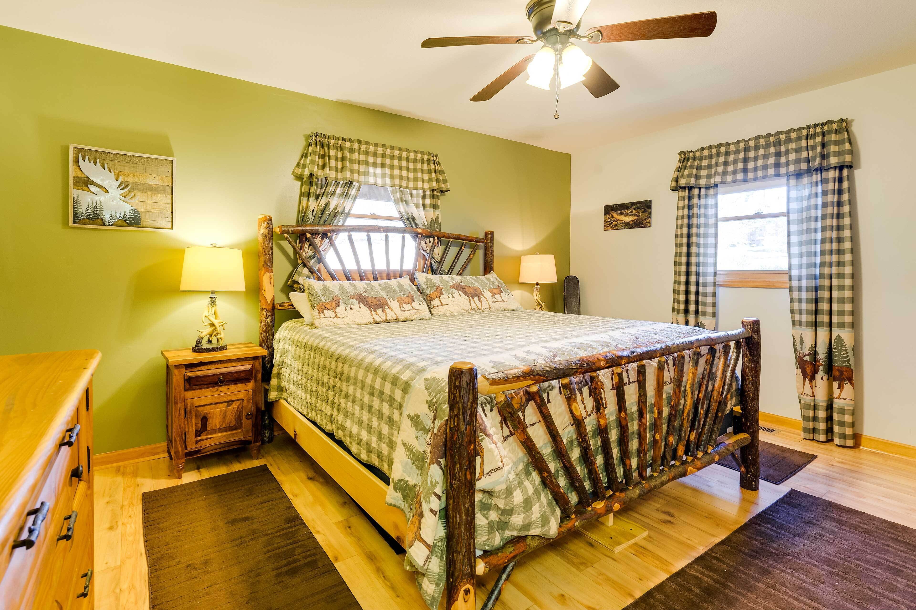 Un dormitorio con cama de madera, paredes verdes y un ventilador de techo.