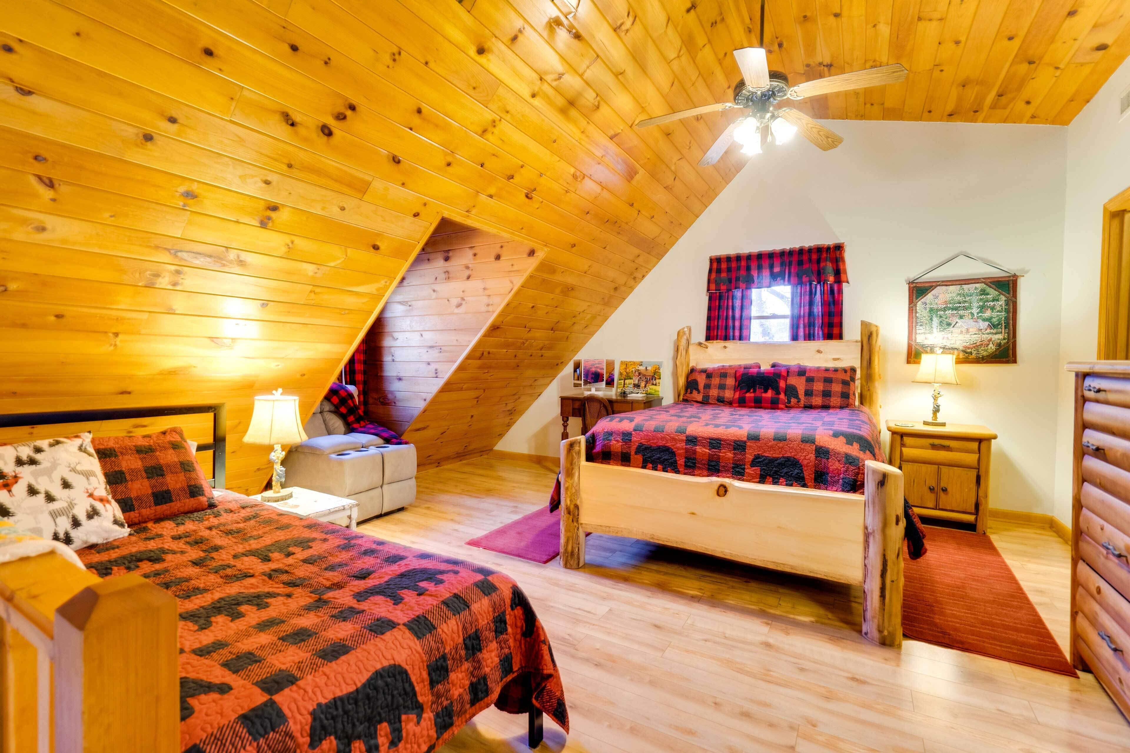 A cozy attic bedroom with two wooden beds, a ceiling fan, and a sloped ceiling.