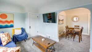 Un salon avec un canapé bleu, une table basse et un téléviseur fixé au mur.