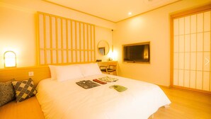 Habitación de hotel con cama, mesita de noche, lámpara y puerta corredera.