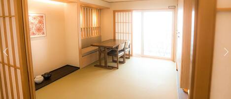 Una habitación tradicional japonesa con suelo de tatami, una mesa baja con sillas, puertas correderas y un panel shoji.