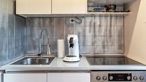 A kitchen with a coffee machine, a sink, and a digital clock displaying 17:41.