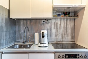 Une cuisine équipée d’une machine à café, d’un évier et d’une horloge numérique affichant 17h41.