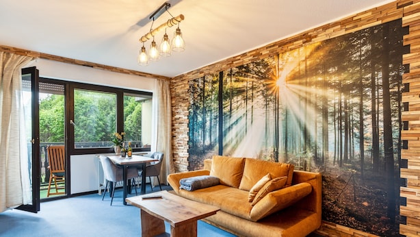 A modern living room with a large window, a sofa, a coffee table, and a dining area.