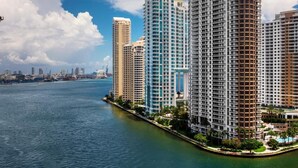 Un hotel moderno de gran altura con varias plantas, vista al agua y un puerto deportivo al fondo.