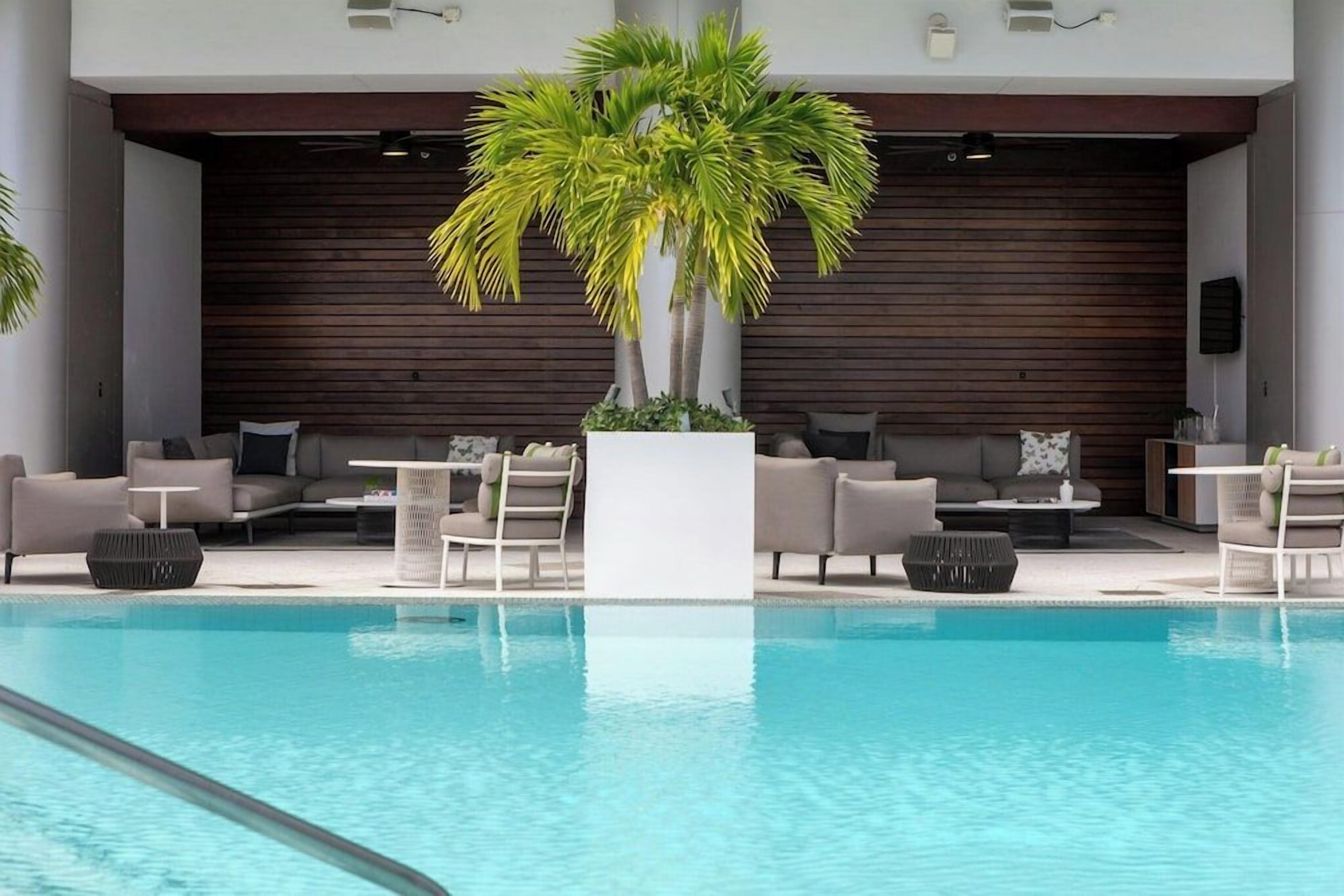 A modern indoor pool area with lounge seating and a central plant.
