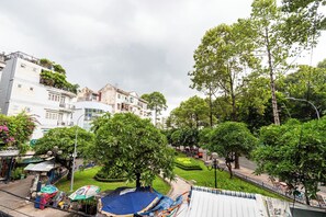 A residential area with multi-story buildings, a small park with trees, and a street with parked cars.
