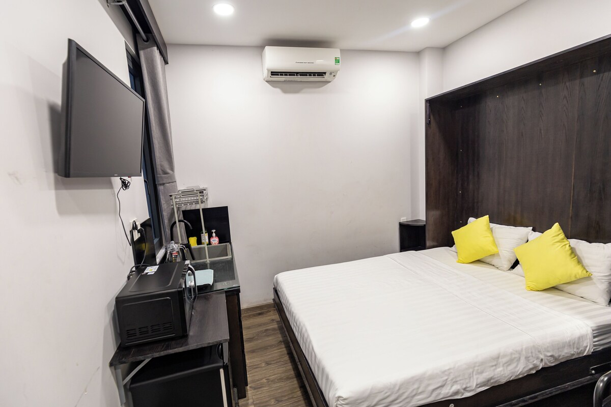 Camera d'albergo con un letto, una scrivania con un computer, una TV a schermo piatto e un condizionatore d'aria.