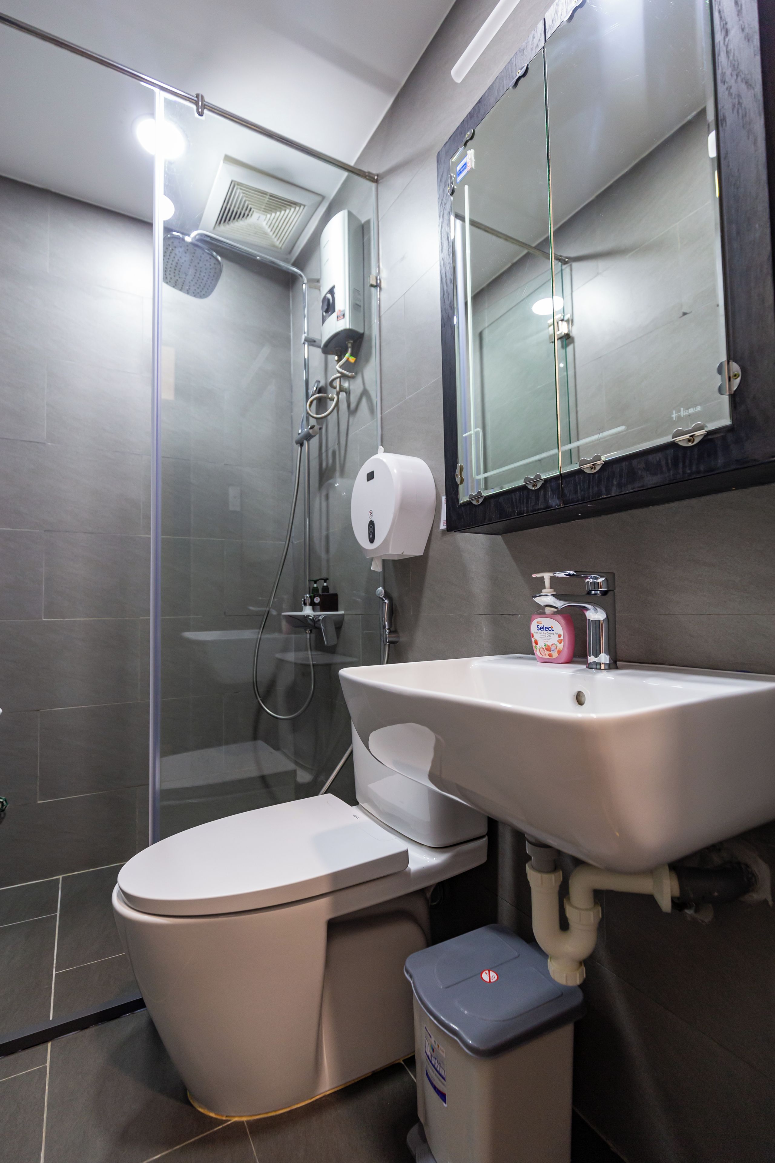 Un baño moderno con inodoro, lavamanos y ducha con mampara de vidrio.