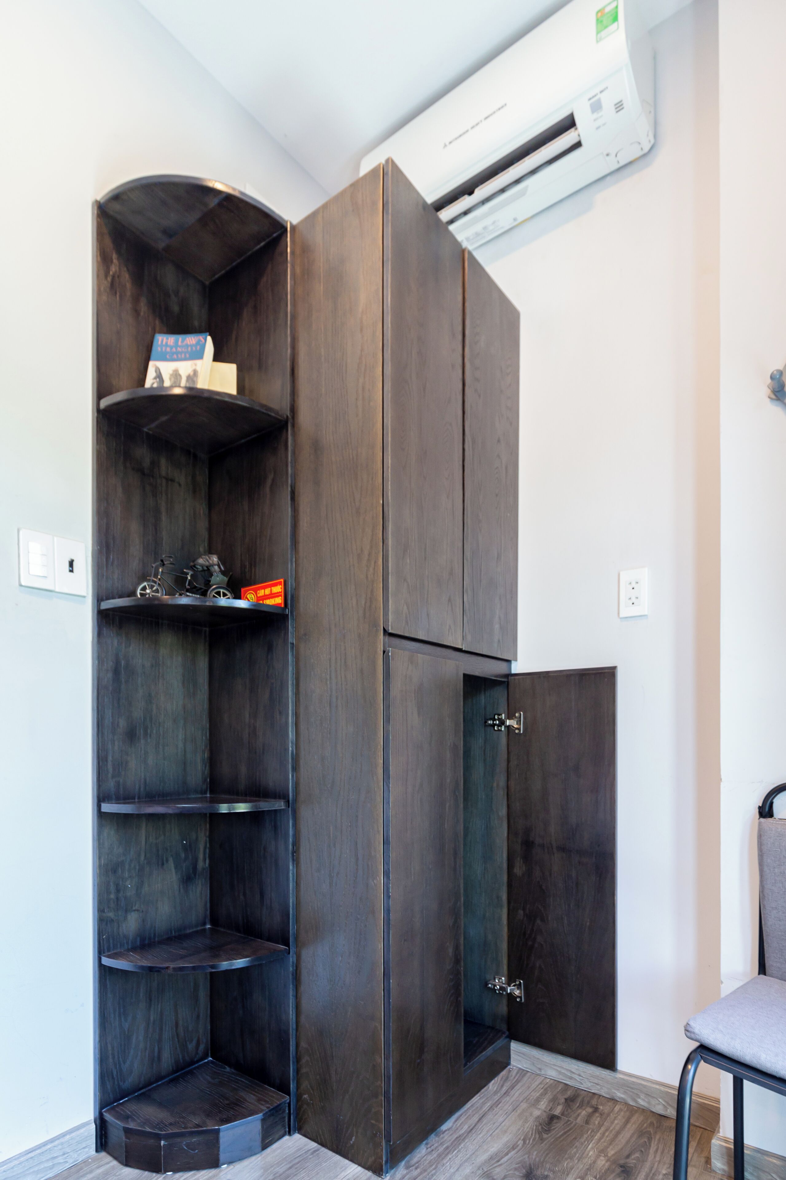 Una esquina con un mueble de madera oscura, una estantería con una bicicleta y una silla.