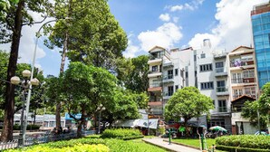A multi-story building with balconies, surrounded by lush greenery and trees.