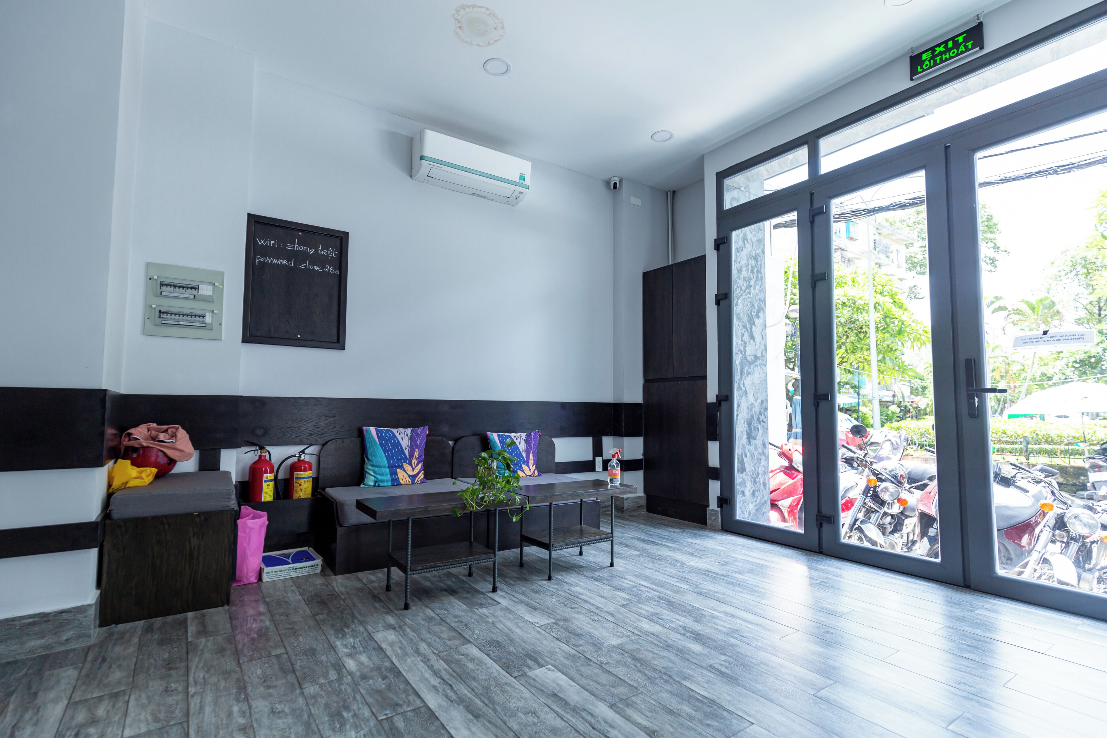 A modern reception area with a black and white color scheme, a seating area with cushions, a fire extinguisher, and a sign indicating WiFi and password.