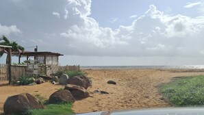 A beach view with a wooden structure and rocks. - Island colors (REMIRE MONTJOLY)