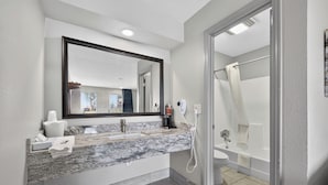 Une salle de bain moderne avec un lavabo en marbre, un grand miroir, une douche et des toilettes.