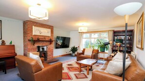 A living room with a fireplace, leather sofas, a coffee table, a TV, and a bookshelf.