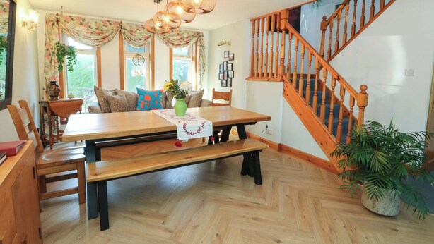 A dining area with a wooden table, benches, and a staircase with wooden railings.