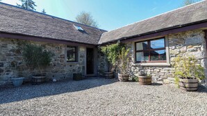 A stone building with a gravel driveway, windows, and potted plants.