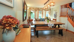 A dining area with a wooden table, benches, and a vase of flowers.