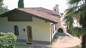 A single-story building with a tiled roof, a wooden door, and a small porch with a bench. - Vacation home with private grounds and pool with panoramic views in Tremosine (Tremosine)