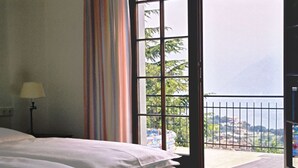 A bedroom with a bed, a lamp, a window with a view of a balcony and landscape. - Vacation home with private grounds and pool with panoramic views in Tremosine (Tremosine)