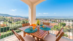 Een balkon met een tafel gedekt voor twee personen, uitzicht op het landschap en een balustrade.