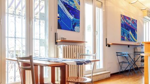 A room with a wooden table, chairs, a radiator, and two windows with decorative iron grilles. - Penthouse with terrace Navigli Bocconi - NavigliApartments  (Milano)