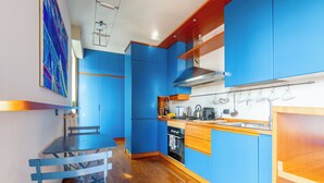 A modern kitchen with blue cabinets, a wooden dining table, and a built-in oven. - Penthouse with terrace Navigli Bocconi - NavigliApartments  (Milano)