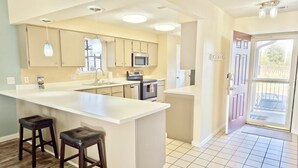 A modern kitchen with a large island, stainless steel appliances, and a view to the outside.