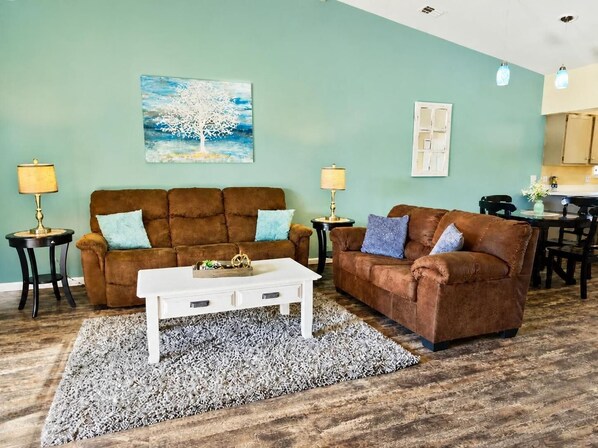 A living room with two brown sofas, a white coffee table, and a patterned rug. - By Strip~Pools-Hot Tub~Dry Sauna~Fitness Rm (Branson)