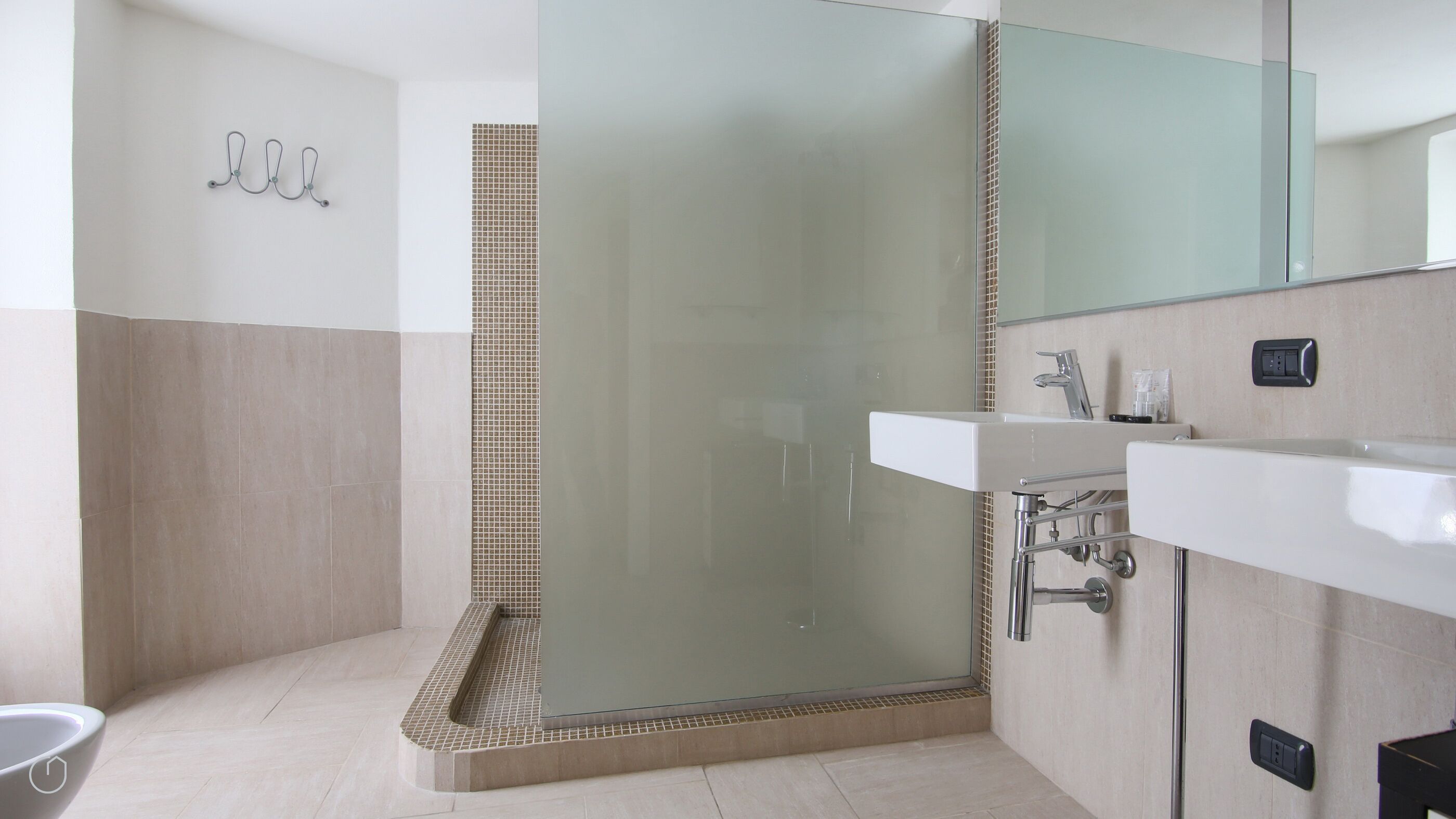 A modern bathroom with a glass shower enclosure, a white sink, and a mirror.