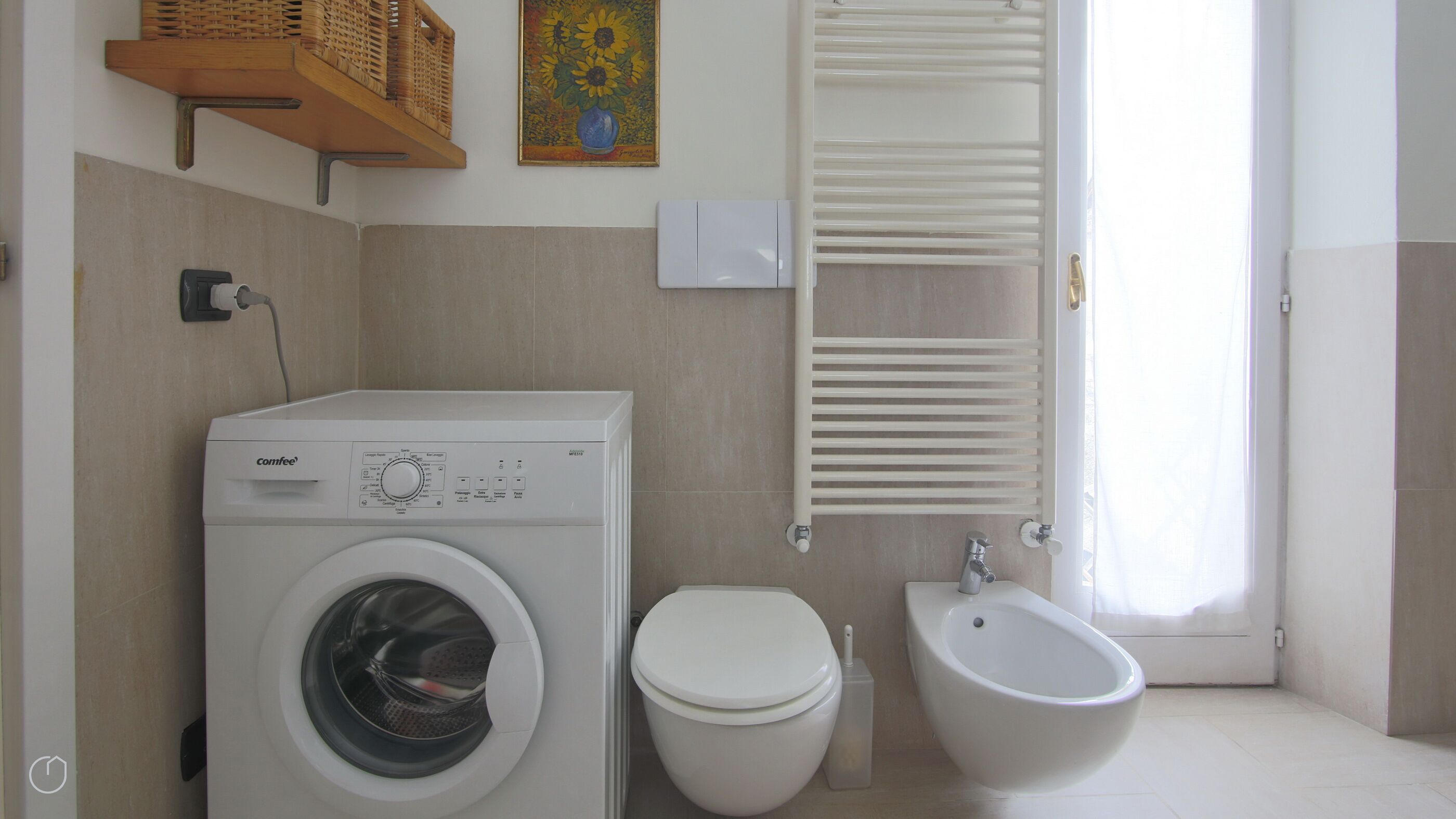 A compact bathroom with a washing machine, toilet, bidet, and a towel rack.