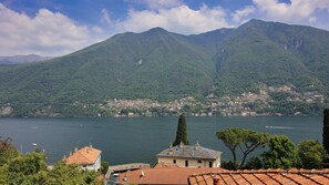 A coastal town with terraced houses, a mountain backdrop, and a body of water. - Italianway - Riva Soldino 9 (Laglio)