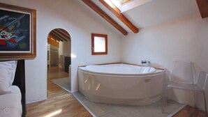 A modern bathroom with a large bathtub, a wooden ceiling, and a framed abstract painting. - Italianway - Riva Soldino 9 (Laglio)