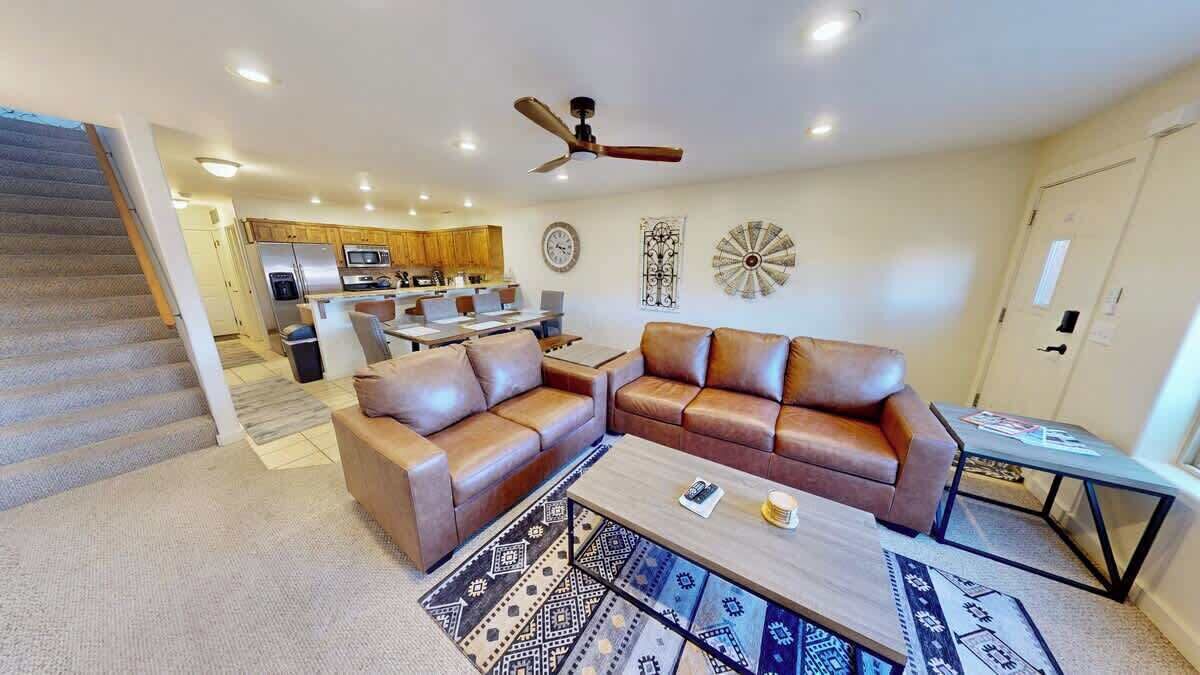 A modern living room with a sectional sofa, a coffee table, and a dining area in the background.