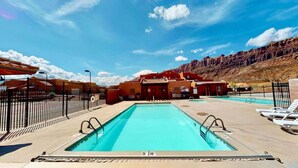 A pool area with a clear sky, a mountain backdrop, and a building with red walls. - Rim Vistas - 5A8 (Moab)