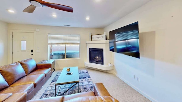 A living room with a leather sofa, a coffee table, a fireplace, and a mounted TV. - Rim Vistas - 5A8 (Moab)