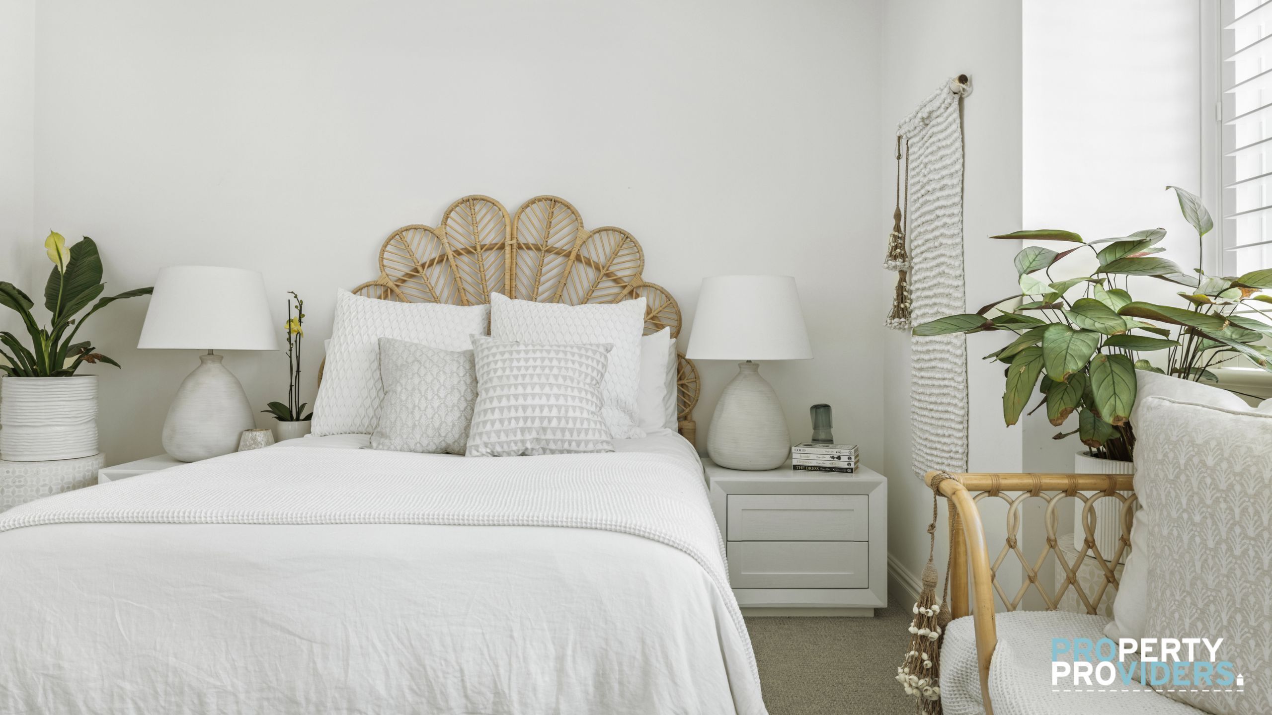 A neatly arranged bedroom with a bed, bedside tables, lamps, and potted plants.