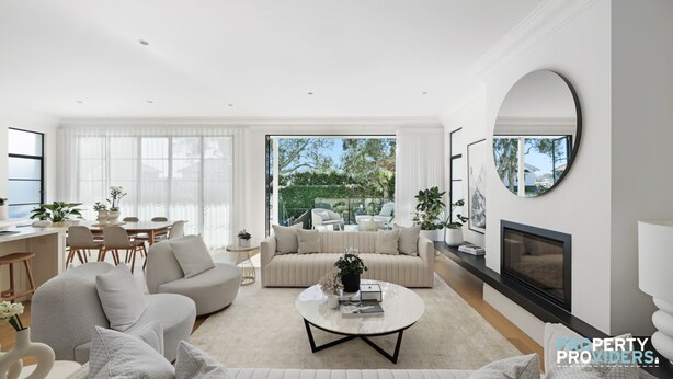 A modern living room with a sofa, coffee table, and a fireplace. There is a dining area with a table and chairs, and a large window offering a view of the outdoors. - Uber Luxury 4 Bed Home with Pool in Mosman (Mosman)