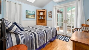 Une chambre à coucher avec un lit, une armoire en bois, un tableau et une vue à travers une porte vitrée.