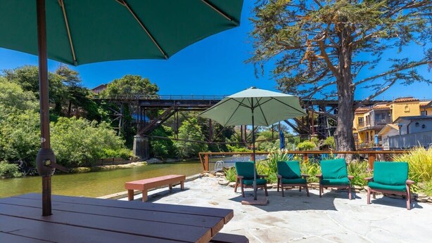 Une terrasse extérieure avec une table en bois, des chaises vertes et un grand parasol.