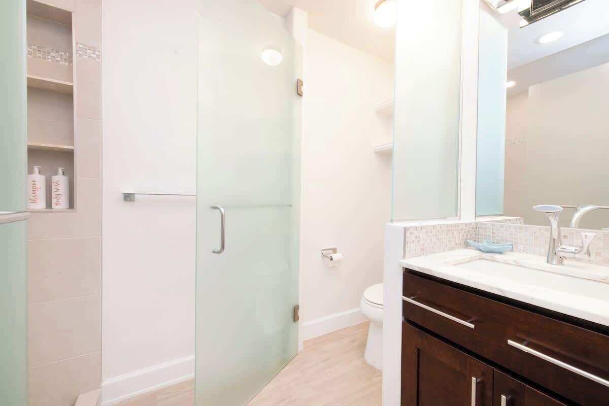 A modern bathroom with a glass shower door, a white toilet, and a vanity with a mirror.