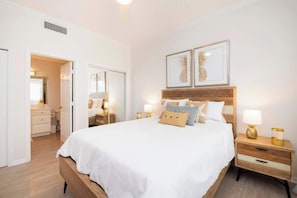A neatly arranged bedroom with a large bed, bedside tables, and framed artwork on the wall.