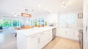 A modern kitchen with white cabinetry, a central island, and a dishwasher. - Crescent Point Condo #9 - 3BR 7 Mile Beach Condo (George Town)