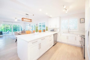 A modern kitchen with white cabinetry, a central island, and a dishwasher. - Crescent Point Condo #9 - 3BR 7 Mile Beach Condo (George Town)