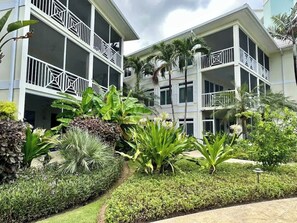 Un hôtel doté de nombreux balcons, d’une végétation luxuriante et d’un jardin bien entretenu.