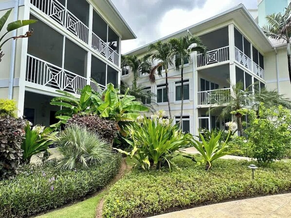 Un hôtel doté de nombreux balcons, d’une végétation luxuriante et d’un jardin bien entretenu.