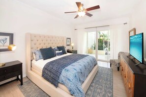 Une chambre dotée d’un grand lit, d’un ventilateur de plafond, d’une télévision et offrant une vue sur l’extérieur.