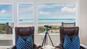 A room with two leather chairs facing a large window overlooking a beach. - The Lookout - Beachfront, amazing views, spacious home (Cloverdale)